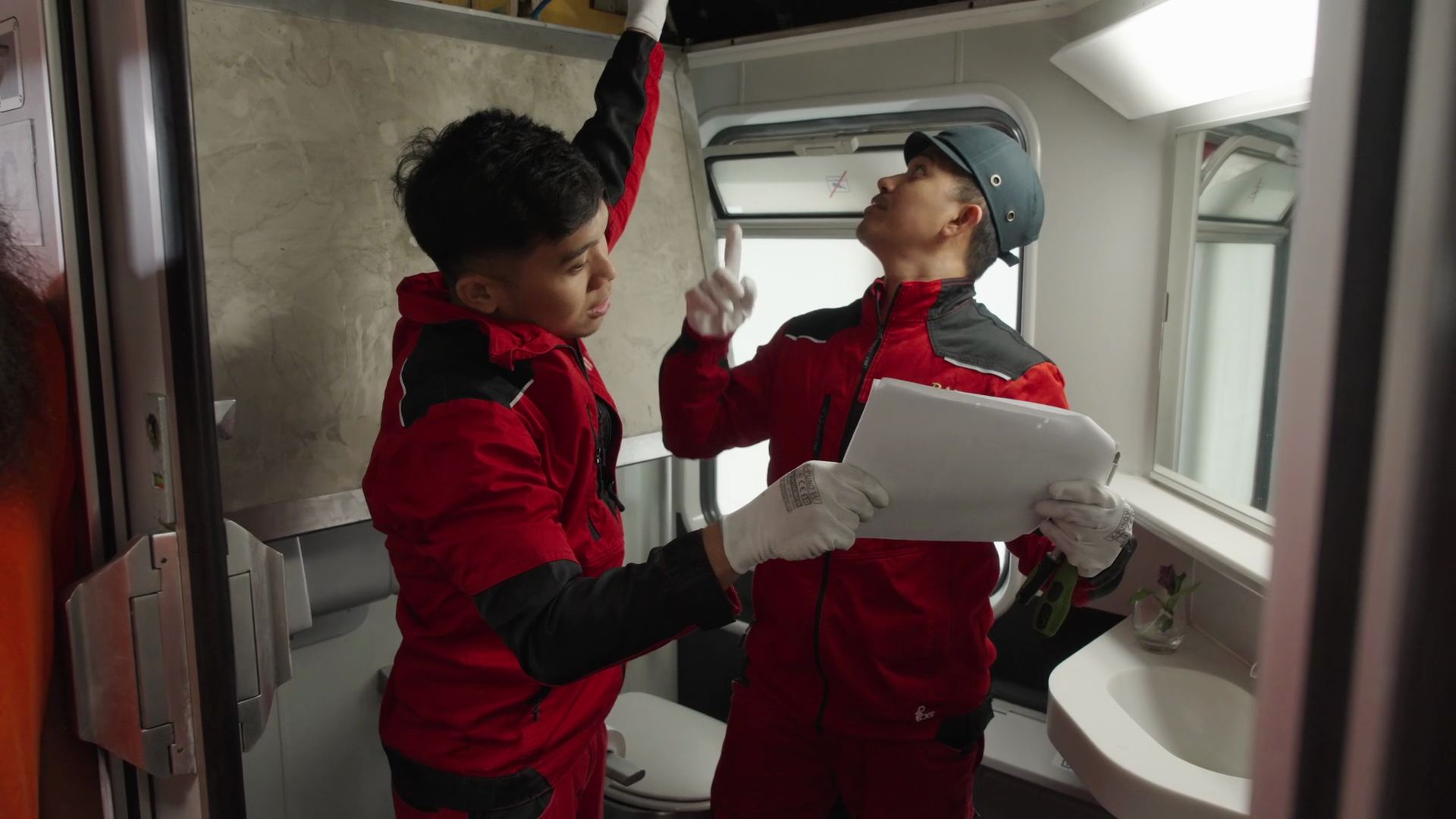 Two colleagues repairing the interior of a train washroom