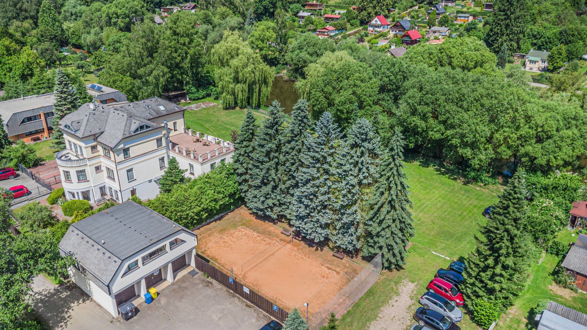 Aerial view of the accommodation grounds with the clay court, gardens and parking
