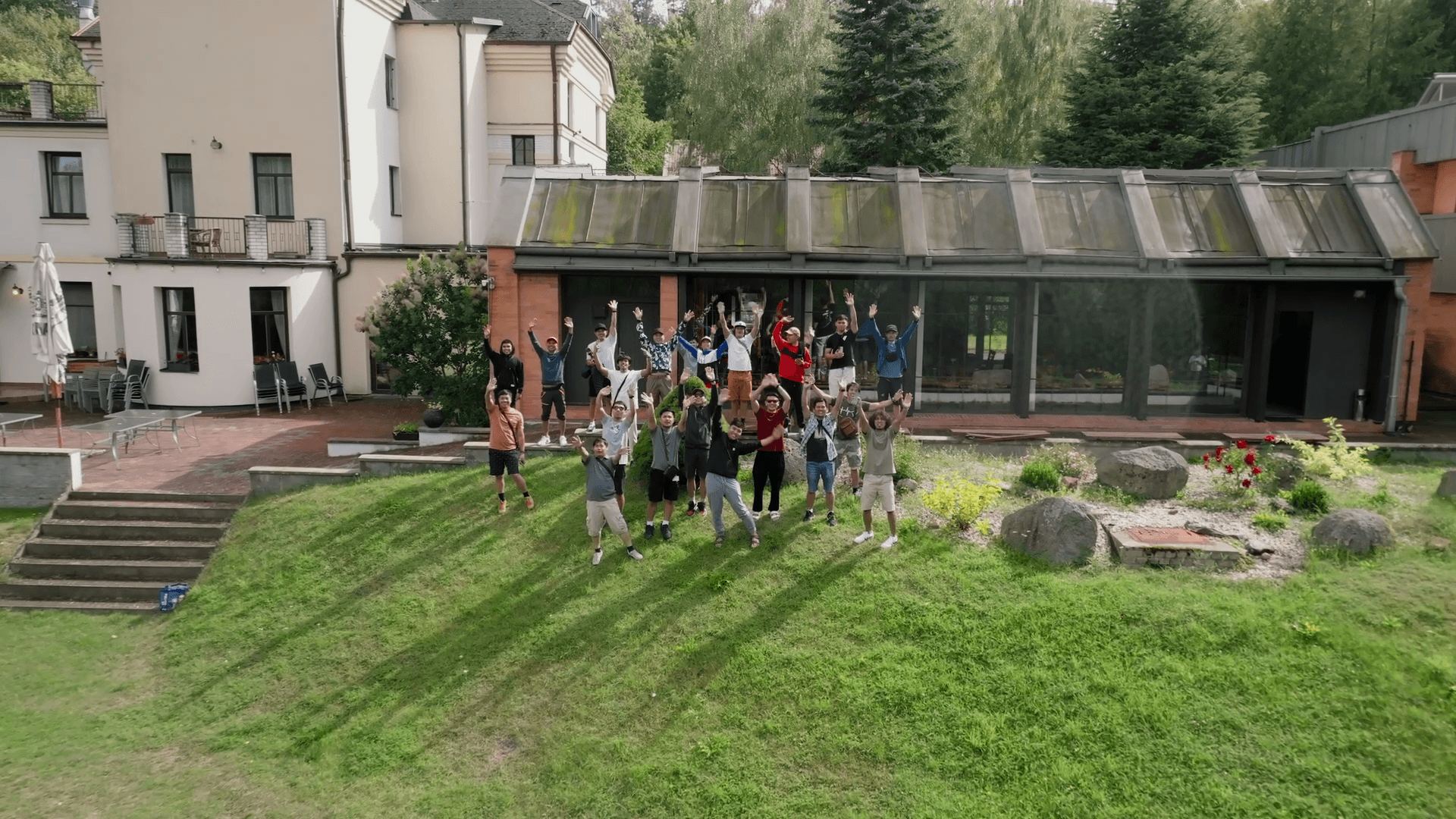 The team on the lawn in front of the accommodation with their arms raised