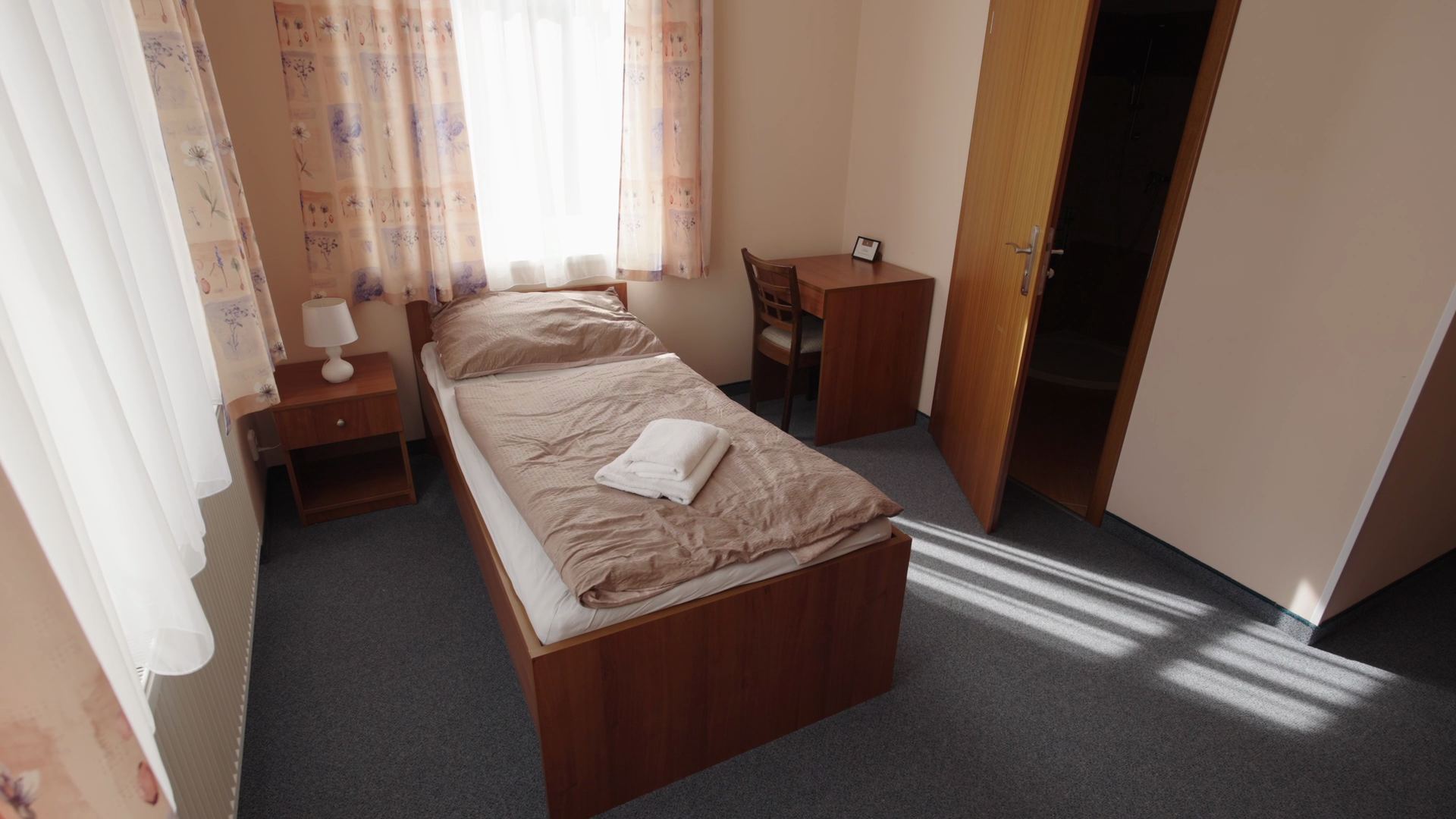 Single room in the accommodation with a bed, desk and wardrobe