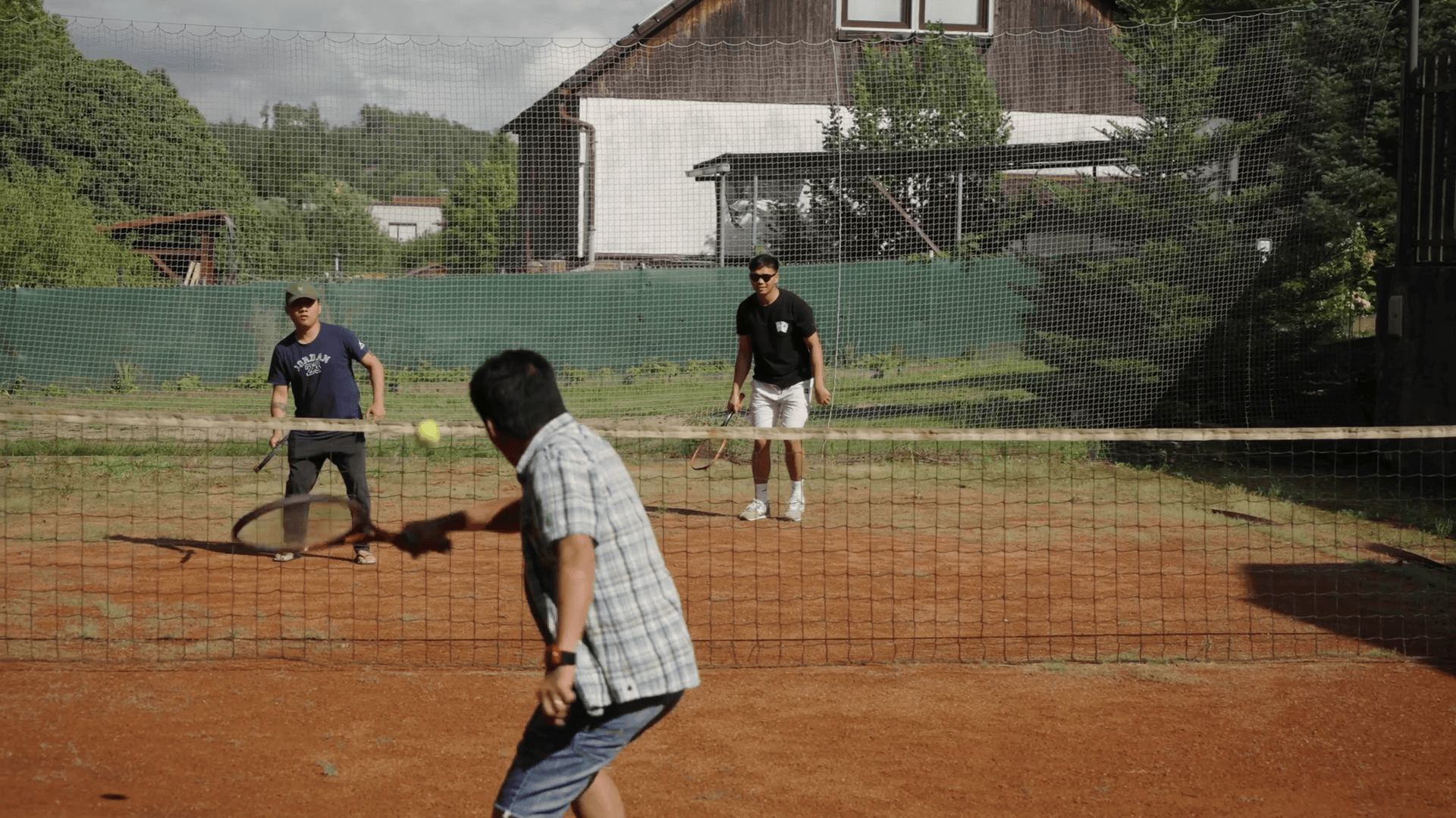 Three colleagues playing tennis on the clay court