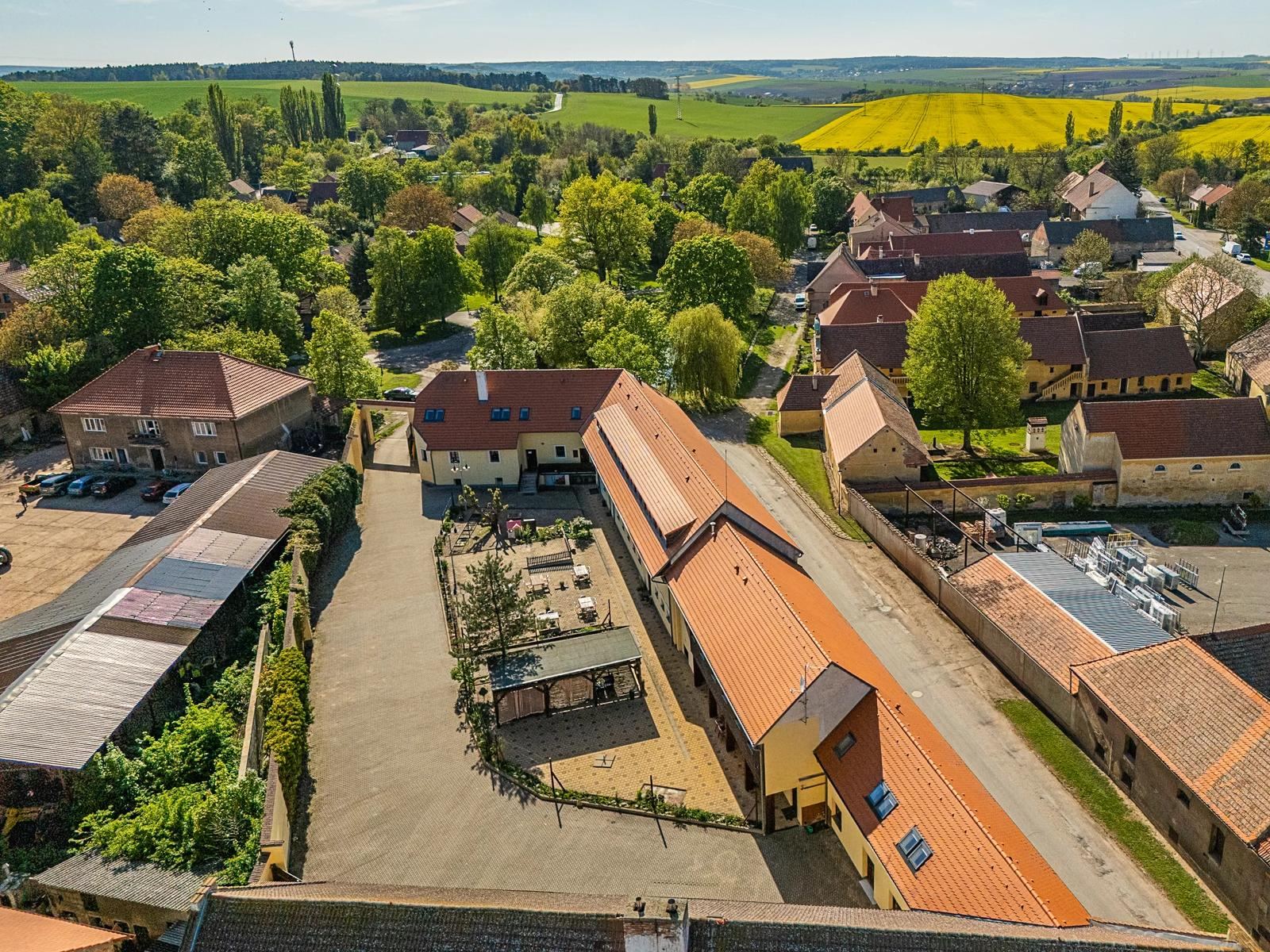 Aerial view of the accommodation and the village around it, with fields on the horizon